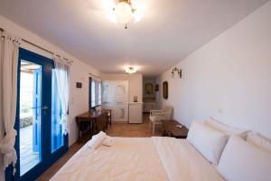 a bedroom with a white bed with a blue door at Villa Victoria with Sea View and Two Private Pools in Elia