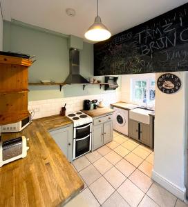 a kitchen with white appliances and a chalkboard on the wall at Charming cottage retreat with garden - sleeps 12 in Bristol