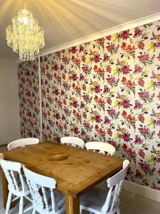 a dining room table with white chairs and a floral wallpaper at Charming cottage retreat with garden - sleeps 12 in Bristol