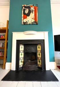 a fireplace in a living room with a painting on the wall at Charming cottage retreat with garden - sleeps 12 in Bristol