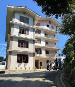 un edificio alto con gente parada frente a él en THE RETREAT PEILING en Pemayangtse