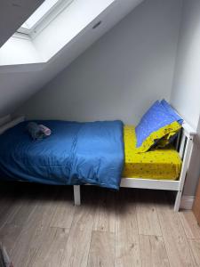 Comfy Friendly Stay في لندن: سرير مع بطانيه زرقاء وصفراء في الغرفه