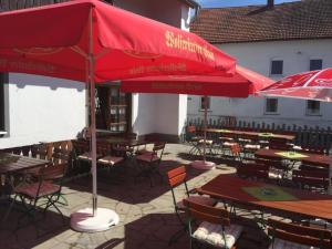 un patio con mesas y sillas y sombrillas rojas en Zum Zacherwirt, en Hengersberg