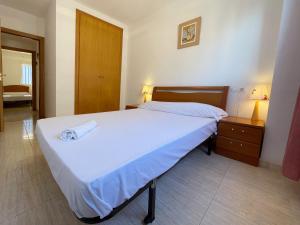a bedroom with a large white bed and a nightstand at Apartamentos Vistamar Marina D'Or 1º línea 3000 in El Borseral +43 photos