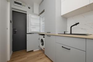 華沙的住宿－Pretty Studio Apartment in Warsaw City Centre by Renters，白色的厨房配有水槽和洗衣机