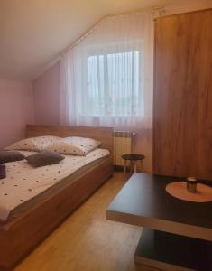 Schlafzimmer mit einem Bett, einem Fenster und einem Tisch in der Unterkunft Apartament 'Siwy Dom' 