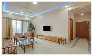 a living room with a table and a tv on a wall at Welcome Service Apartments in Mumbai