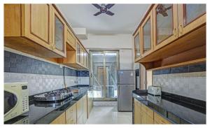 La cuisine est équipée d'armoires en bois et d'un réfrigérateur en acier inoxydable. dans l'établissement Welcome Service Apartments, à Mumbai