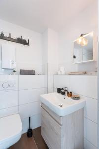 La salle de bains blanche est pourvue d'un lavabo et de toilettes. dans l'établissement - Cozy apartment in the heart of Duisburg with New York Design & Betten & Sofa - 5 Mins Central Station Hbf - Big TV & WiFi -·, à Duisbourg