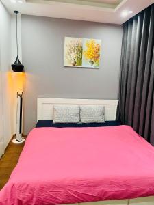1 dormitorio con 1 cama con colcha rosa en Vinhomes Green Bay G30332, en Hanói