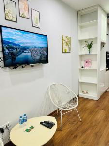 sala de estar con mesa y TV en la pared en Vinhomes Green Bay G30332, en Hanói