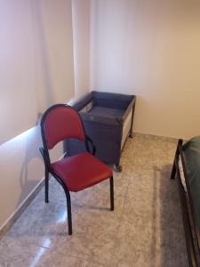 una silla roja sentada junto a una cama en una habitación en departamento equipado Pioneros en Zapala