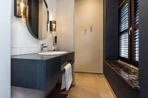 W łazience znajduje się umywalka i lustro. w obiekcie MERICI Hotel Sittard w mieście Sittard