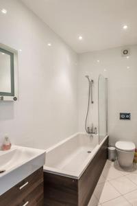 a bathroom with a tub and a toilet and a sink at Bay View - Private parking, beach views, central location in Kent
