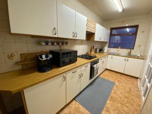 a kitchen with white cabinets and a microwave at Bungalow in Badsey, north of the Cotswolds in Badsey