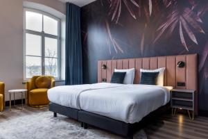 sypialnia z dużym łóżkiem i żółtym krzesłem w obiekcie MERICI Hotel Sittard w mieście Sittard