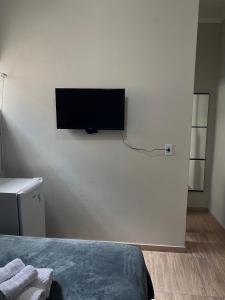 a bedroom with a flat screen tv on the wall at Quarto privativo no centro 01 in Itapira