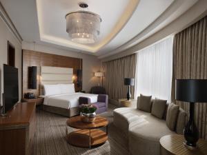 a hotel room with a bed and a couch at Grand Millennium Sulaimani in As Sulaymānīyah