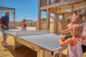 a group of people standing around a ping pong table at Mobil Home les pieds dans l'eau in Sarzeau