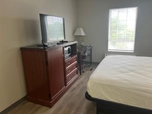 a bedroom with a bed and a dresser with a television on it at Baymont by Wyndham Lakeland in Lakeland