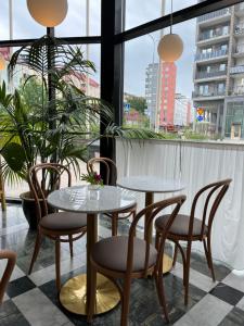 two tables and chairs in a room with windows at 2Home Hotel Apartments in Solna