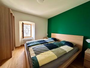 1 dormitorio con 1 cama con pared verde en Alpe di Caviano, en Castel San Pietro