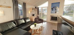 uma sala de estar com um sofá de couro preto e uma mesa em Ferienhaus Freibeuterweg 13 - b51130 em Lübeck