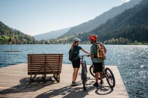 zwei Leute stehen auf einem Steg mit ihren Fahrrädern in der Unterkunft Familien- Sportresort BRENNSEEHOF in Feld am See