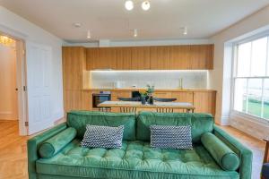 sala de estar con sofá verde y cocina en The Lookout - Stylish penthouse with sea views en Kent