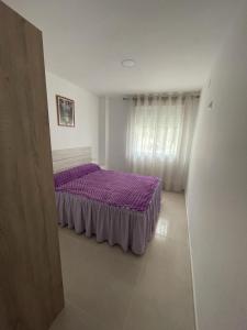 1 dormitorio con cama morada y ventana en Apartamento Islu, en Peñíscola