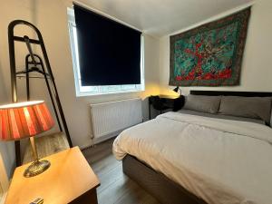 1 dormitorio con cama, lámpara y ventana en Bethnal Green Rooms R3 en Londres