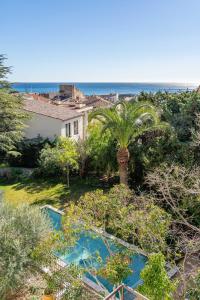 a view of a garden with a palm tree and the ocean at Le petit clos St Devote par Dodo à Cassis in Cassis
