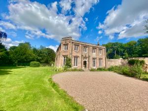 una antigua casa de piedra con una entrada de grava en Chillingham Manor en Chillingham