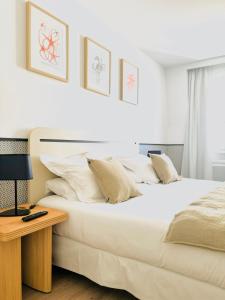 a bedroom with two beds and a table with a lamp at Hôtel De La Marine in Arromanches-les-Bains
