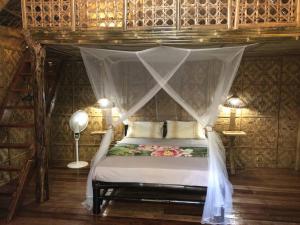 ein Schlafzimmer mit einem Himmelbett in der Unterkunft Maison bamboo, in Pila