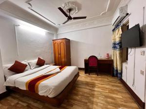 加德滿都的住宿－跋涉之家酒店，一间卧室配有一张床、一张书桌和一台电视
