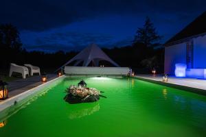 una piscina de agua verde con una tienda en el fondo en Nocfond Lodges, en Langon