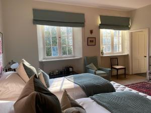 a bedroom with two beds and a chair and windows at Chillingham Manor in Chillingham