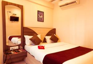 a hotel room with two beds and a mirror at OYO Hotel Royal Grand Near Chhatrapati Shivaji International Airport in Mumbai