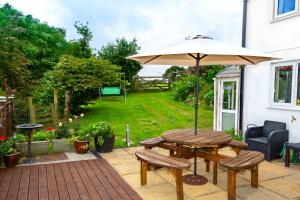 eine Terrasse mit einem Tisch und einem Sonnenschirm in der Unterkunft Trepartridge Cottage Llanelli in Llanelli