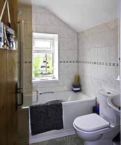 ein Bad mit einer Badewanne, einem WC und einem Fenster in der Unterkunft Trepartridge Cottage Llanelli in Llanelli