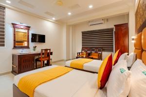 a hotel room with two beds and a desk at Daan Orchid Residency in Kottayam