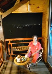 une femme assise sur une chaise à une table dans l'établissement Farm cô chú Tuấn Hà, à Đà Lạt