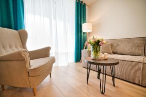 a living room with a couch and a table with flowers on it at Laguna Beskidów Resort - Apartament A83 in Zarzecze