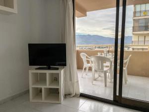 a living room with a television and a table with chairs at Apartamentos Benicassim 3000 in Benicàssim