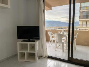 - un salon avec une télévision et une table avec des chaises dans l'établissement Apartamentos Benicassim 3000, à Benicàssim