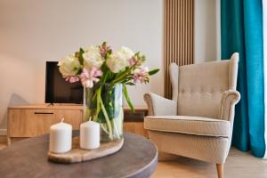 a vase of flowers on a table in a living room at Laguna Beskidów Resort - Apartament A83 in Zarzecze