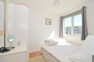a white bedroom with a bed and a window at 74 Sandown Bay Holiday Park, Isle of Wight in Sandown