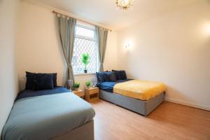 a bedroom with two beds and a window at Rochdale Train STN, Large House in Rochdale