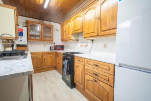 a kitchen with wooden cabinets and black appliances at Rochdale Train STN, Large House in Rochdale